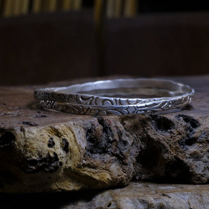 Pair of handmade interlocking sterling silver bangles with textured arabesque pattern