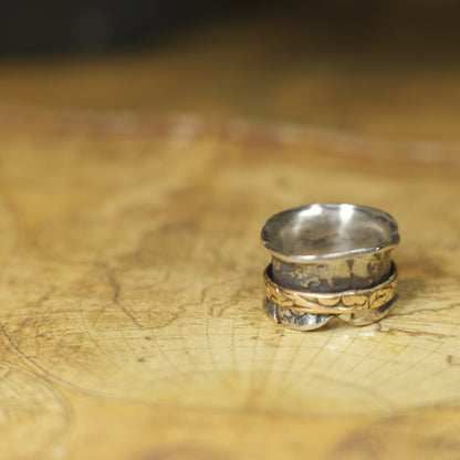 Handmade 9ct yellow gold spinner ring on a wide textured oxidised sterling silver band
