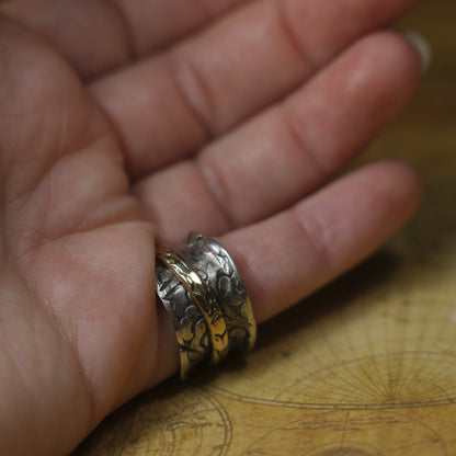 Handmade 9ct yellow gold spinner ring on a wide textured oxidised sterling silver band