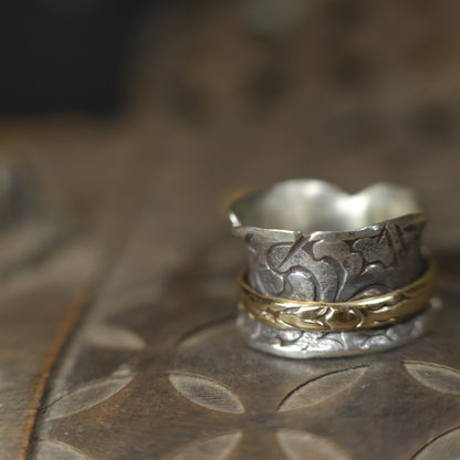 Handmade 9ct yellow gold spinner ring on a wide textured oxidised sterling silver band