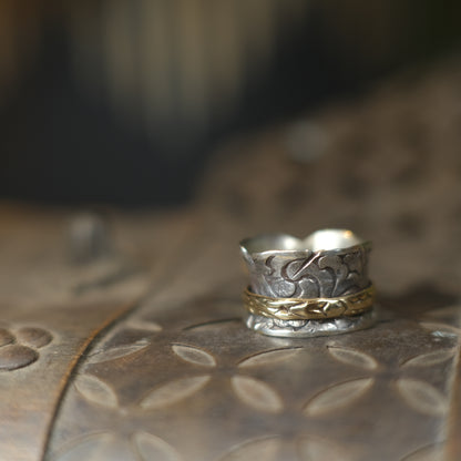 Handmade 9ct yellow gold spinner ring on a wide textured oxidised sterling silver band